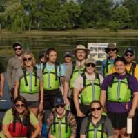 group of 15 in lifejackets standing in front of a lake
